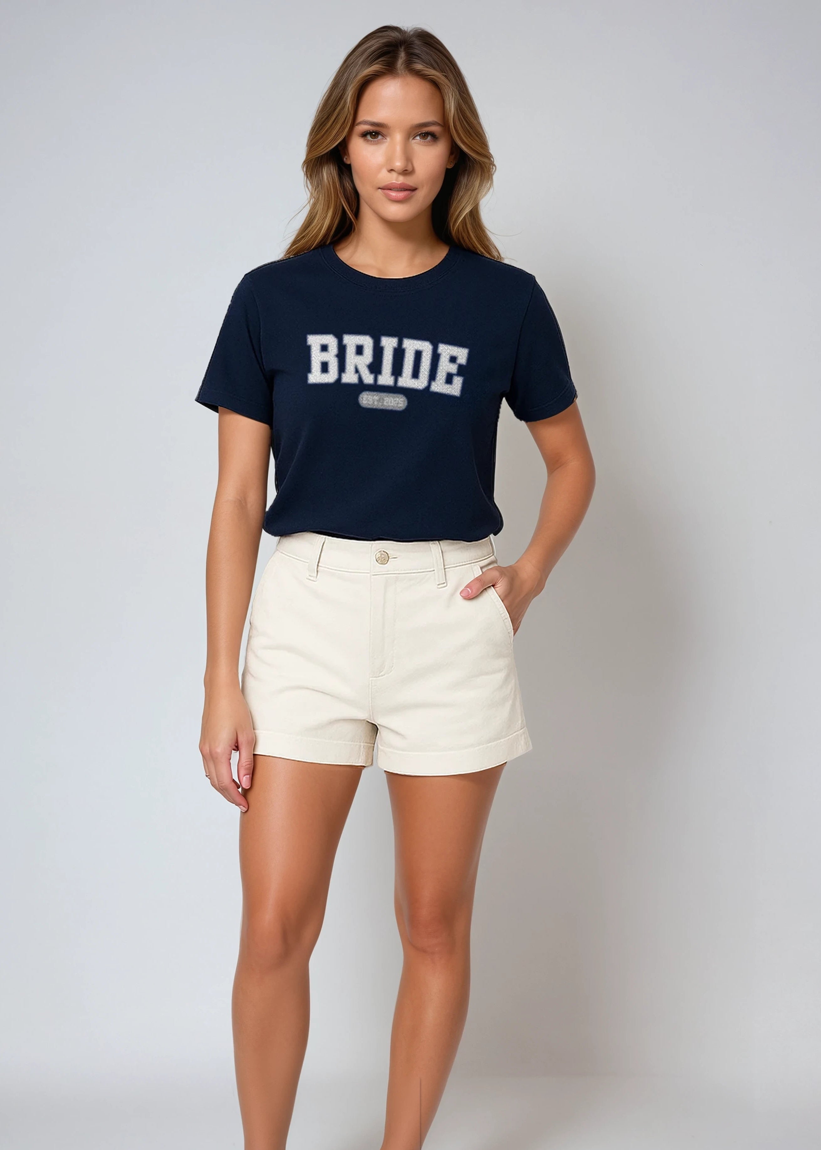 Woman wearing a navy 'BRIDE' t-shirt with white shorts on a plain background